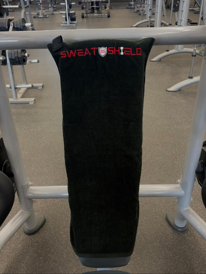 Black sweat shield with 'Sweat Shield' branding on a workout bench.