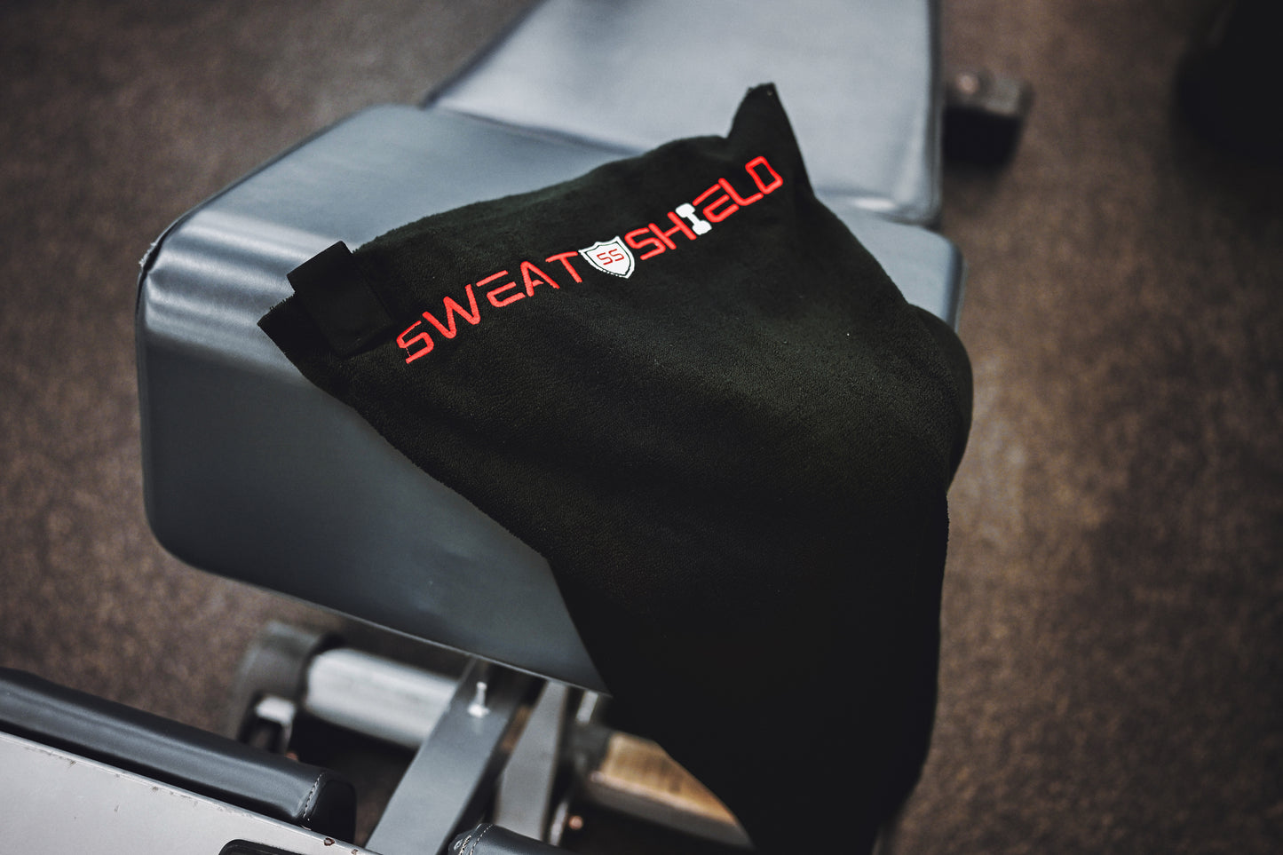 Black sweatshirt with 'SweatShed' logo on a gym bench